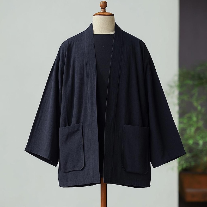 May include: A dark blue lightweight cotton kimono with two large pockets. The kimono is open at the front and has a simple design.