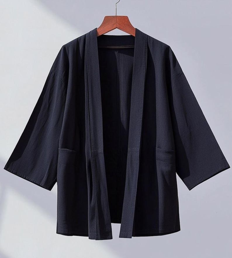 May include: A dark blue lightweight kimono-style jacket with long sleeves and a wide open front. The jacket has two pockets on the sides and is made of a soft, comfortable fabric.