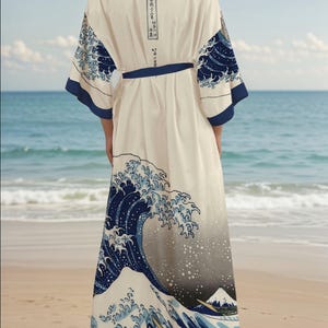 May include: A white silk robe with a blue and white print of The Great Wave off Kanagawa by Katsushika Hokusai. The robe has a blue sash and long sleeves.