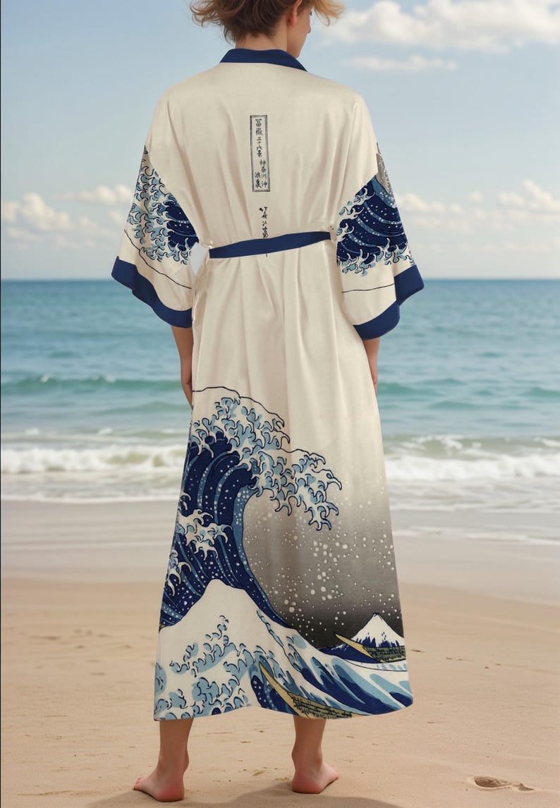 May include: A white silk robe with a blue and white print of The Great Wave off Kanagawa by Katsushika Hokusai. The robe has a blue sash and long sleeves.