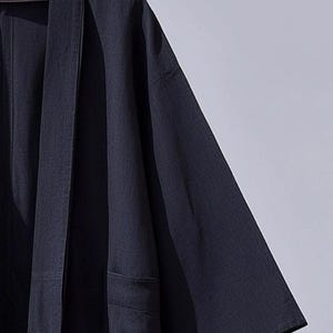 May include: A dark blue kimono-style robe with a long, open front and long sleeves. The robe is made of a lightweight fabric and has a simple, elegant design.