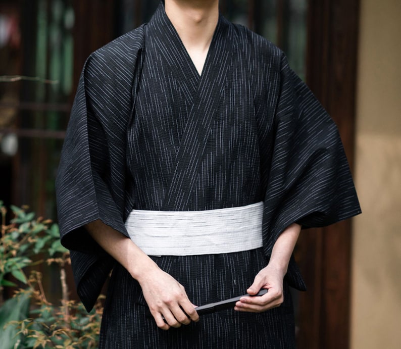 May include: A black and white striped yukata with a white sash. The yukata is a traditional Japanese robe worn during the summer months.