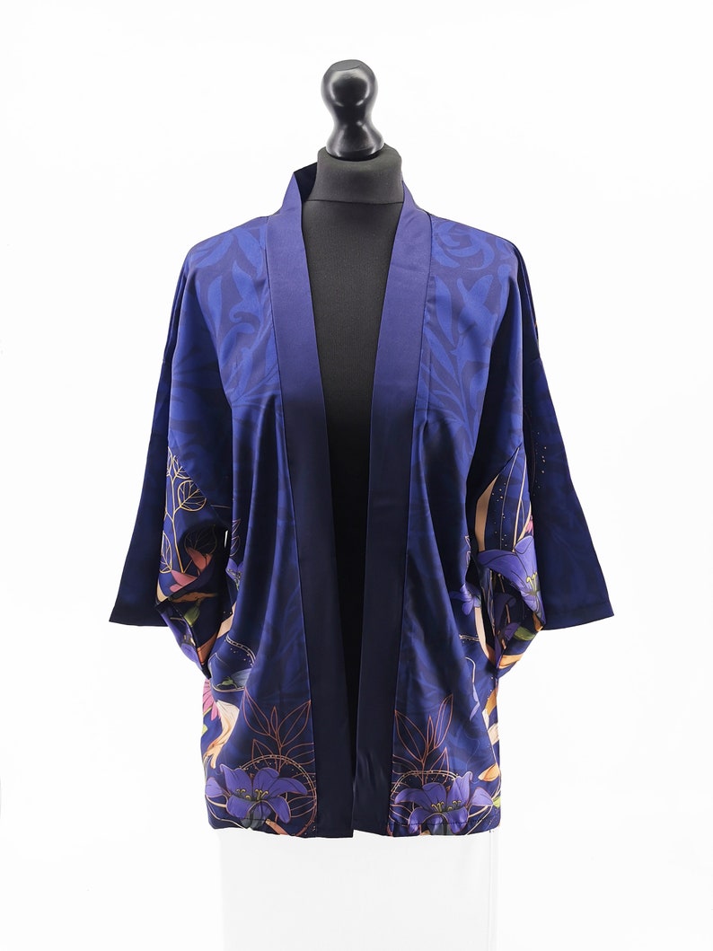 Puede incluir: Un kimono azul marino con estampado floral. El kimono tiene manga larga y cuello ancho.
