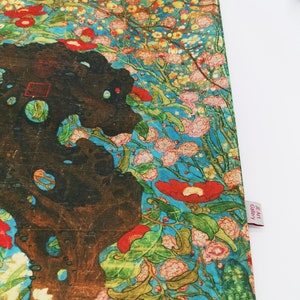 May include: A tote bag with a colorful floral print featuring red, pink, and white flowers on a blue background. The bag has a turquoise handle and a small tag that says "JE Art Gallery".