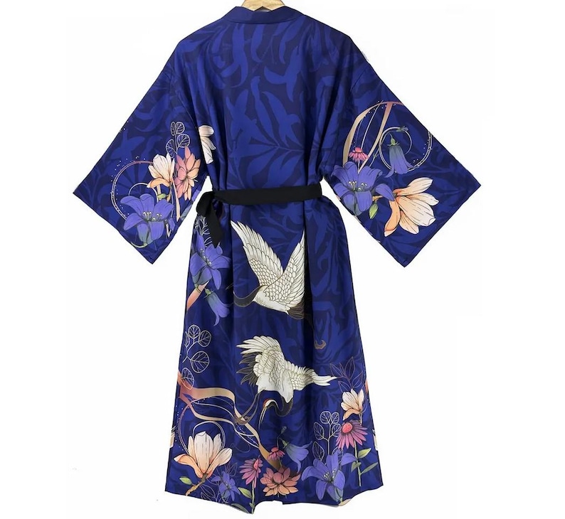 Puede incluir: Una bata de seda azul con estampado floral y de gr&uacute;as. La bata tiene una cinta negra y mangas largas.