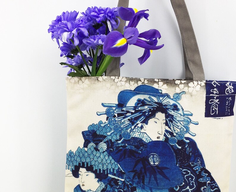 May include: A tote bag with a floral design and a Japanese print of a woman in a blue and white kimono. The text on the bag reads "寿" in Japanese.