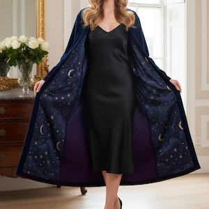 May include: A long, navy blue robe with a celestial design on the interior lining. The lining features a dark blue background with gold stars and crescent moons. The robe is open, revealing a black dress.