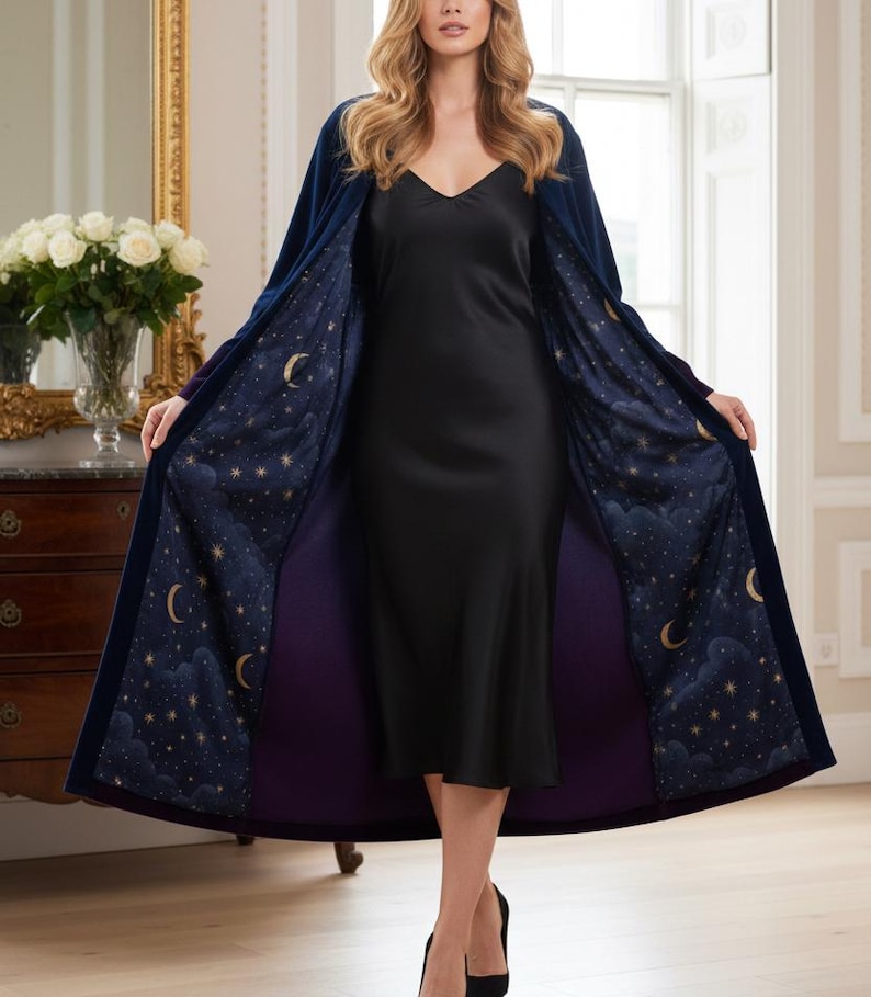 May include: A long, navy blue robe with a celestial design on the interior lining. The lining features a dark blue background with gold stars and crescent moons. The robe is open, revealing a black dress.