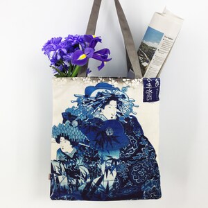 May include: A white tote bag with blue and white Japanese-inspired artwork featuring a woman in a traditional kimono. The bag has grey straps and the text "東海道" is printed on the side.