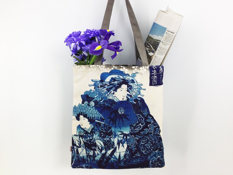 May include: A white tote bag with blue and white Japanese-inspired artwork featuring a woman in a traditional kimono. The bag has grey straps and the text "東海道" is printed on the side.