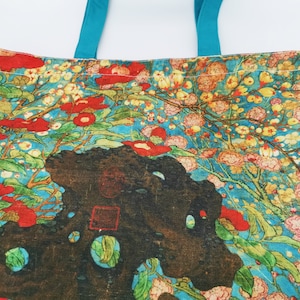 May include: A tote bag with a floral design featuring red, pink, and yellow flowers on a blue background. The bag has turquoise handles.