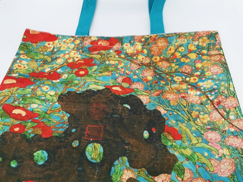 May include: A tote bag with a floral design featuring red, pink, and yellow flowers on a blue background. The bag has turquoise handles.