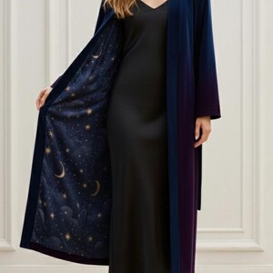 May include: A long, open-front robe in navy blue, with a purple trim and a celestial-themed lining. The lining features a dark blue background with gold stars and crescent moons. The robe is made of a soft, flowing fabric.