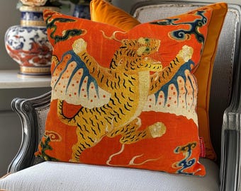 Könnte beinhalten: Orangefarbener Kissenbezug mit einem goldenen und schwarzen Tiger mit Flügeln. Der Tiger springt und hat einen wilden Ausdruck. Der Hintergrund ist rot-orange mit weißen Wolken.