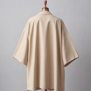 May include: A beige short-sleeved shirt with a collared neckline. The shirt is made of a smooth, lightweight fabric and has a relaxed fit.