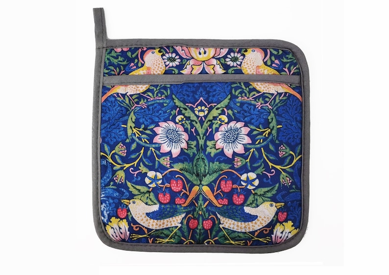 May include: A blue and green pot holder with a floral and bird pattern. The pot holder has a gray border and a loop for hanging.