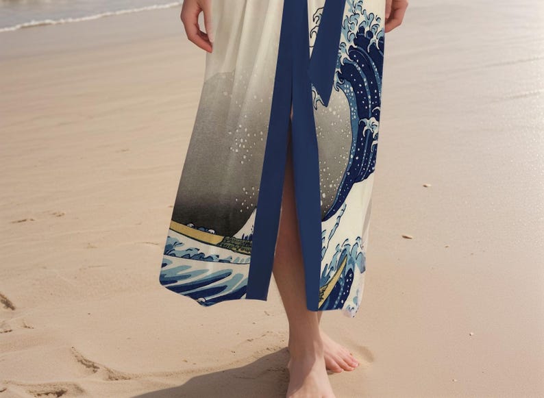 May include: A white maxi dress with a blue and white print of a wave. The dress has a deep V-neckline and a side slit.