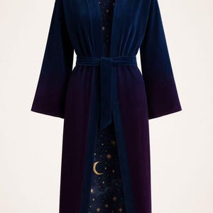 May include: A long, velvet robe in navy blue and deep purple, with a matching belt. The interior lining features a celestial design of a crescent moon and stars on a dark blue background. The robe has wide sleeves.