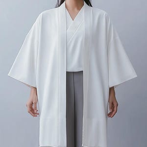 May include: A white kimono with long sleeves and a wide collar. The kimono is open in the front, revealing a white undershirt and gray pants.