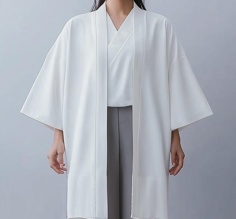 May include: A white kimono with long sleeves and a wide collar. The kimono is open in the front, revealing a white undershirt and gray pants.