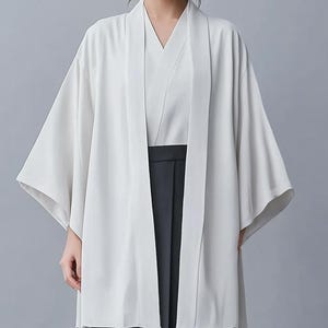 May include: A white kimono with long sleeves and a wide collar. The kimono is open in the front, revealing a white undershirt and black pants.