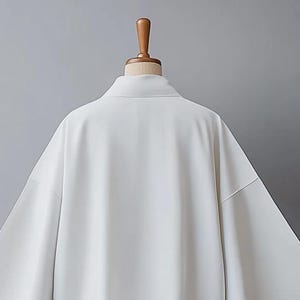May include: A white long-sleeved shirt with a collar and a relaxed fit.