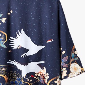 Puede incluir: Un kimono azul marino con una gr&uacute;a blanca y un patr&oacute;n floral. El kimono tiene un ribete dorado y un acento rojo en la gr&uacute;a.