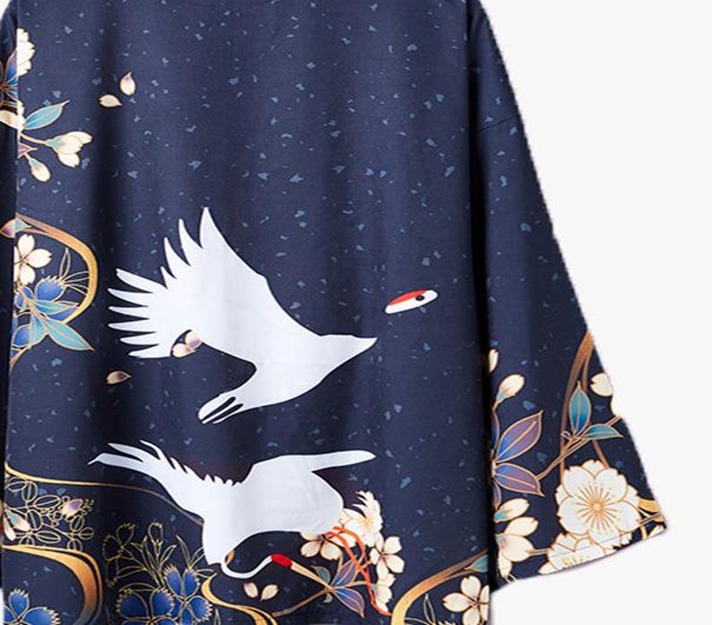 Puede incluir: Un kimono azul marino con una gr&uacute;a blanca y un patr&oacute;n floral. El kimono tiene un ribete dorado y un acento rojo en la gr&uacute;a.