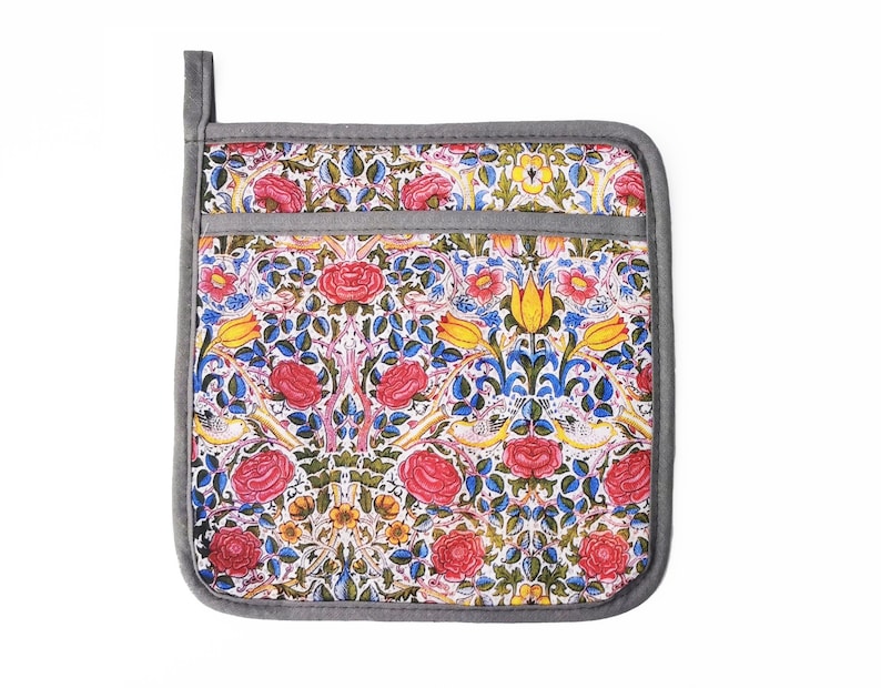 May include: A gray and white pot holder with a floral pattern featuring red, yellow, and blue flowers. The pot holder has a pocket on the front.