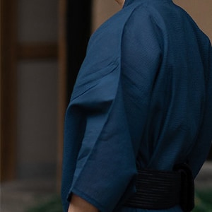 May include: A dark blue kimono with a black belt. The kimono is made of a soft, lightweight fabric and has a relaxed fit.