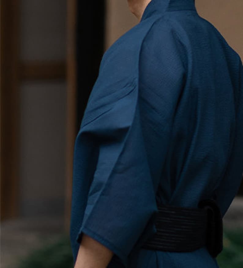 May include: A dark blue kimono with a black belt. The kimono is made of a soft, lightweight fabric and has a relaxed fit.