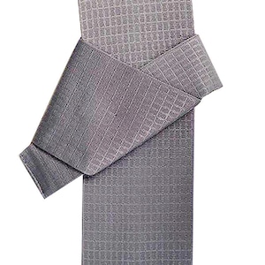 May include: A gray waffle weave kitchen towel folded in half. The towel is made of a soft, absorbent material and is perfect for drying dishes, wiping spills, and cleaning surfaces.