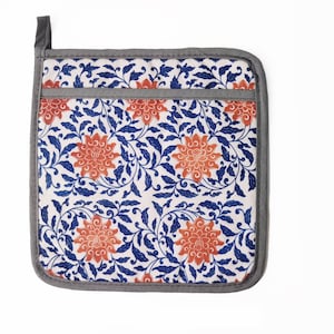 May include: A square pot holder with a floral pattern. The pot holder is white with blue and orange floral designs. The pot holder has a gray border.