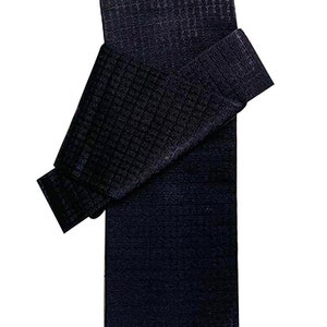 May include: A dark blue, waffle-textured fabric folded in half. The fabric is folded in a way that shows the texture of the fabric.