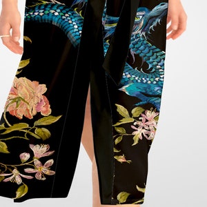 May include: A black wrap skirt with a blue dragon and floral embroidery. The skirt has a side slit and a black sash.