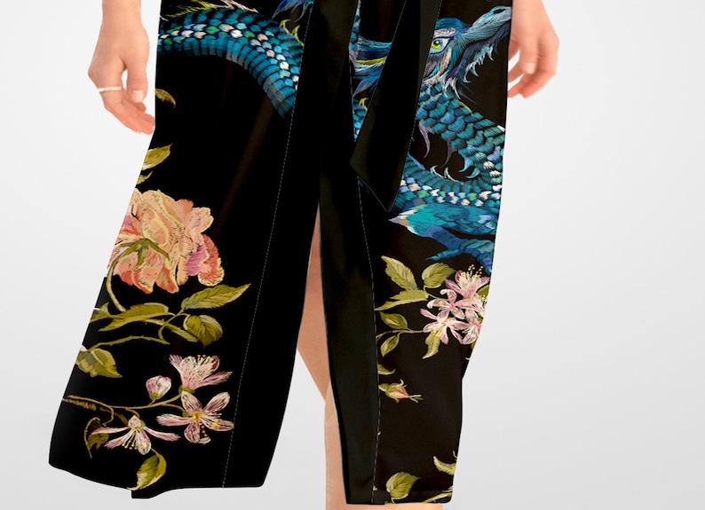 May include: A black wrap skirt with a blue dragon and floral embroidery. The skirt has a side slit and a black sash.