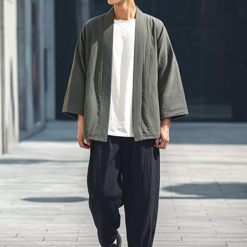 May include: A green kimono-style jacket, white t-shirt, and black trousers. The jacket has a relaxed fit and wide sleeves. The trousers are loose-fitting. The outfit is casual and comfortable, suitable for everyday wear.