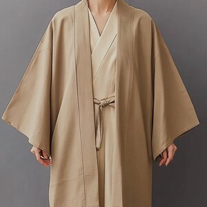 May include: A long, beige kimono with a wide, open collar and long sleeves. The kimono is tied at the waist with a sash.