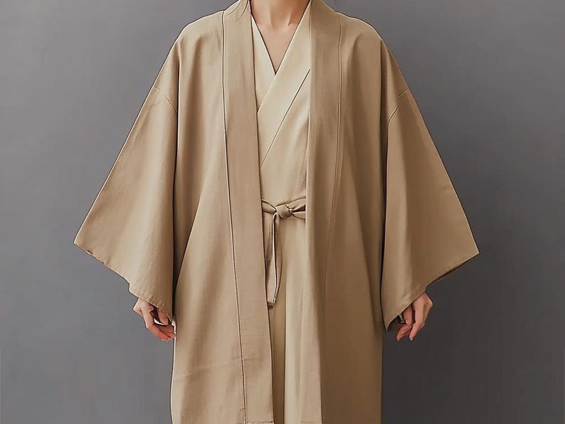 May include: A long, beige kimono with a wide, open collar and long sleeves. The kimono is tied at the waist with a sash.