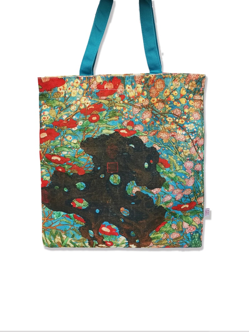 May include: A turquoise tote bag with a floral print featuring red, pink, and white flowers on a blue background. The bag has a black and brown design in the center.
