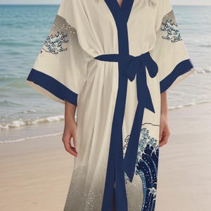May include: A white robe with a blue and white wave pattern. The robe has a navy blue sash and is tied at the waist. The robe is made of a soft, silky material.