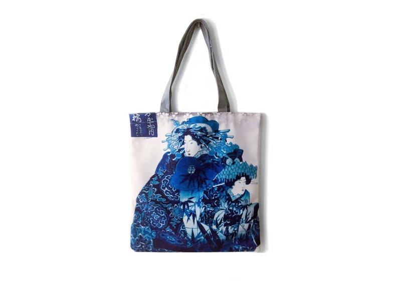 May include: A white tote bag with a blue and white Japanese-inspired print featuring two figures in traditional clothing. The text "浮世絵" is printed on the bag.