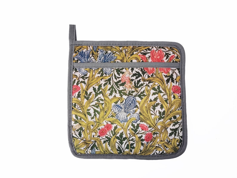 May include: A gray and white pot holder with a floral pattern. The pattern features yellow, green, blue, and red flowers and leaves.
