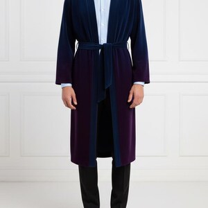May include: A long, two-tone robe in navy blue and deep purple, with a matching belt. The robe has a velvet texture and is worn over a light blue dress shirt and black pants. The robe's design features a navy blue trim.