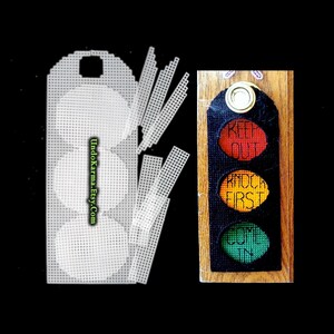 May include: A plastic canvas craft kit featuring a traffic light design with three circular cutouts and separate strips, alongside a finished black fabric traffic light sign with red, yellow, and green circles labeled KEEP OUT, KNOCK FIRST, and COME IN.