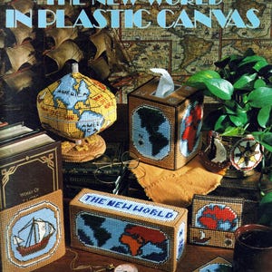 May include: A craft leaflet titled "The New World in Plastic Canvas" with a picture of a globe, a tissue box cover, a rectangular box, and a coaster, all featuring a world map design. The leaflet is from Leisure Arts and is numbered 1408. The text "9 Designs by Virginia Hockenbury" is at the bottom of the leaflet.