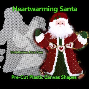 May include: A handcrafted Christmas decoration of Santa Claus made from pre-cut plastic canvas. The Santa figure is dressed in a red coat with white trim and a green vest. The text "Heartwarming Santa" and "Pre-Cut Plastic Canvas Shapes" are visible.