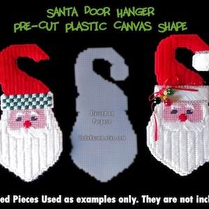 May include: Two pre-cut plastic canvas shapes of Santa Claus, ready for crafting. The shapes are red and white with a green hat and a white beard. The text "SANTA DOOR HANGER" and "PRE-CUT PLASTIC CANVAS SHAPE" is visible at the top of the image.