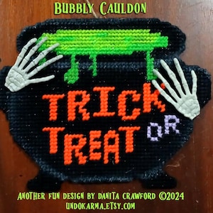 May include: Black cauldron with green slime dripping out, decorated with two white skeleton hands and the text "Trick or Treat".