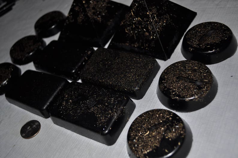 May include: A collection of black, gold-flecked, pyramid-shaped stones. The stones are arranged in a variety of sizes and shapes.